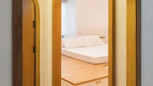 An arched doorway leading to a bedroom with a bed and a wooden cabinet. - Vaeh Viean Silom (Bangkok)