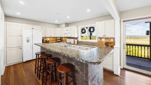 A kitchen with a large island, bar stools, and a view of the outdoors. - A-Frame Home | Ultimate Retreat in Bourbon Country (Coxs Creek)
