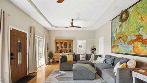 A living room with a sectional sofa, a wooden cabinet, a map on the wall, and a ceiling fan. - A-Frame Home | Ultimate Retreat in Bourbon Country (Coxs Creek)