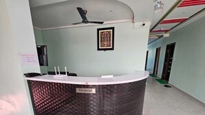 Un mostrador de recepción con una placa identificativa, un ventilador de techo y un cuadro en la pared.