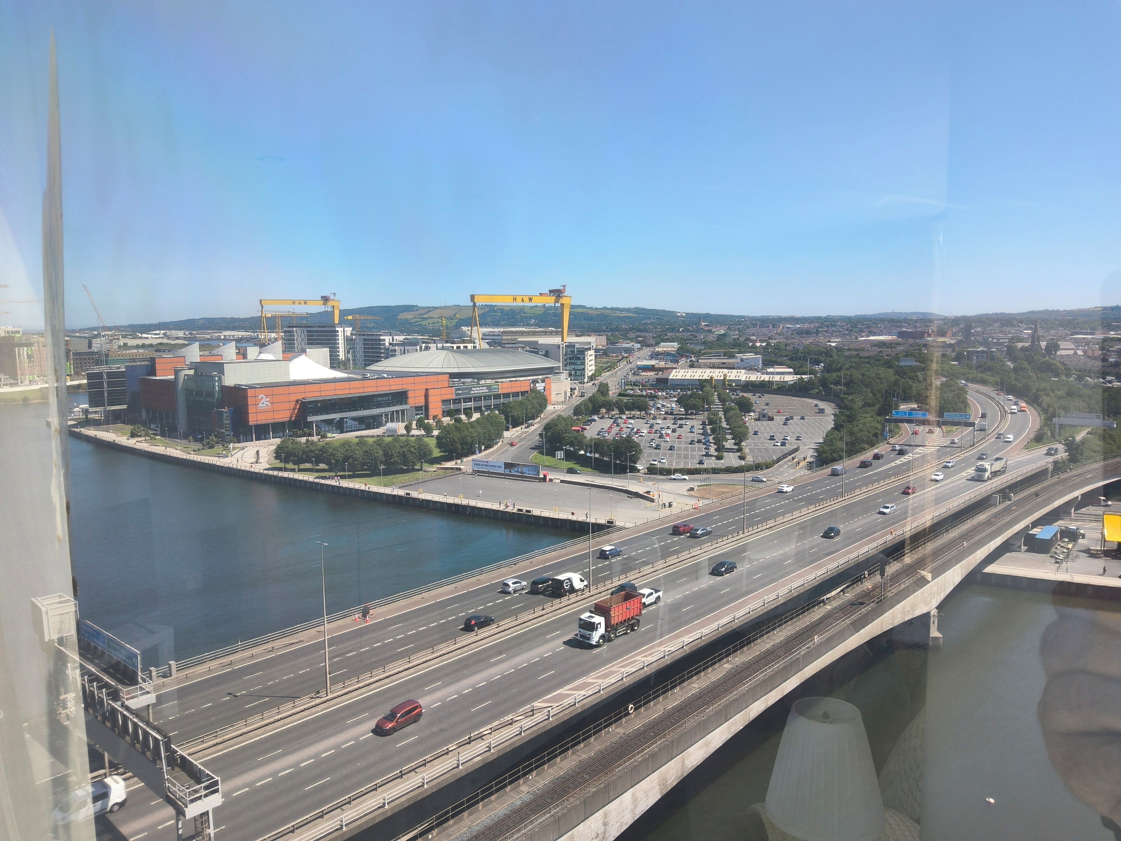 A multi-level highway with several lanes of traffic, a bridge crossing over a body of water, and a large stadium with a distinctive orange and white color scheme.