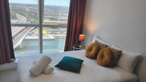 A hotel room with a large bed, a view of a bridge and highway, and a lamp on a side table. - City Centre high rise (Belfast)
