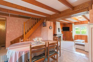 Un intérieur en bois comprenant une table à manger, des chaises, un escalier, un téléviseur et une fenêtre.