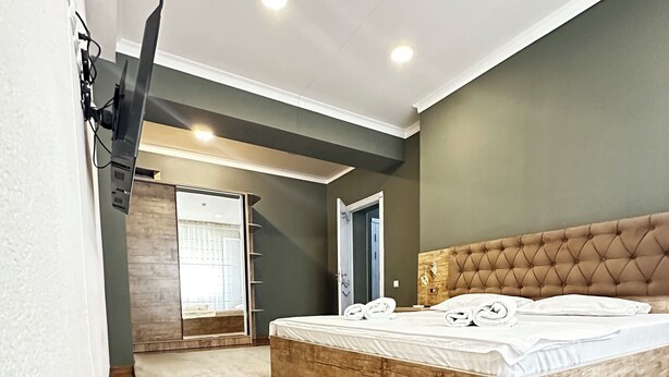 Una camera da letto moderna con pavimento in legno, un letto grande con testiera trapuntata e un armadio a muro.