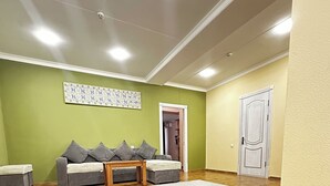 Un ampio soggiorno con pavimento in legno, un tappeto bianco e un divano grigio con cuscini.