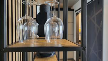 Un coin repas avec une table en bois, des verres à vin en verre transparent et un vase noir.