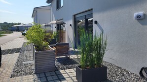 A modern building with a number sign, outdoor seating, and potted plants. - Apartment 'Schlossterrassen 8b' with Private Terrace, Shared Garden and Wi-Fi (Muldestausee)