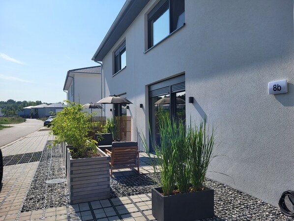 A modern building with a number sign, outdoor seating, and potted plants.