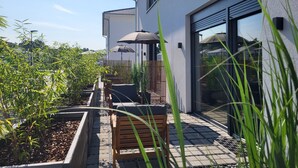 A modern building with a patio area featuring wooden benches and umbrellas, surrounded by greenery. - Apartment 'Schlossterrassen 8b' with Private Terrace, Shared Garden and Wi-Fi (Muldestausee)