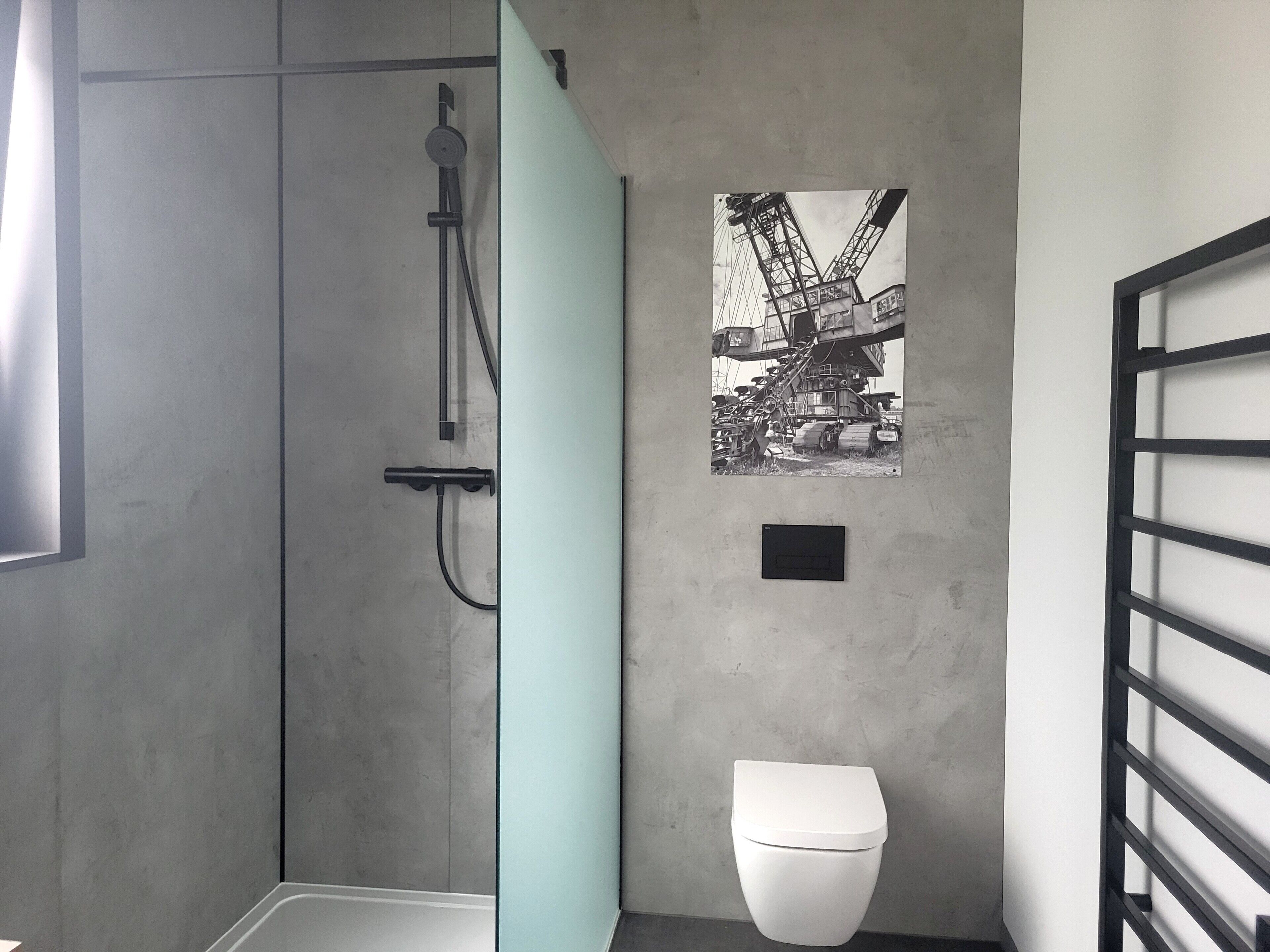 A bathroom with a shower, toilet, and a wall-mounted picture of a construction site.