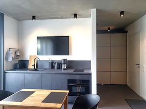Una cocina moderna con televisor de pantalla plana, cafetera y tostadora.