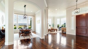 Un amplio salón con pisos de madera, un comedor con una mesa y sillas de madera, y una gran puerta de madera.
