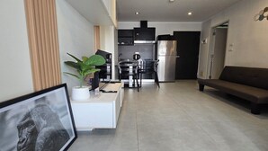 Una cocina moderna con electrodomésticos de acero inoxidable, un comedor con una silla blanco y negro, y un sofá gris.