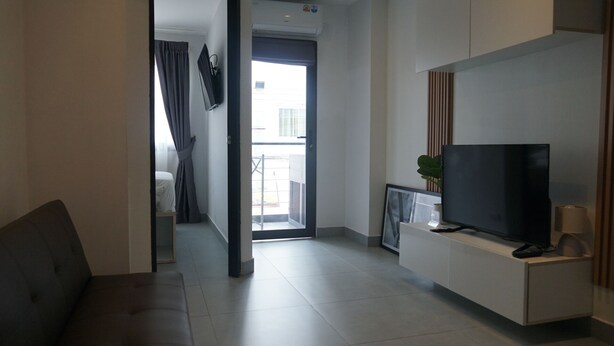 Habitación de hotel moderna con televisor de pantalla plana, un escritorio pequeño y vistas al balcón exterior.