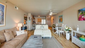 A spacious living area with a sofa, a coffee table, and a dining table with chairs. There is a kitchen in the background with a refrigerator and a sink. - Enjoy oceanfront views from this 2BR condo at Topsail Dunes 3308 in North Topsail Beach. (North Topsail Beach)
