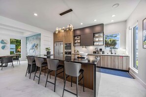 A modern kitchen with a central island, bar stools, and built-in appliances.