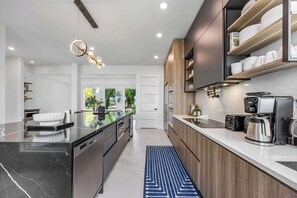 A modern kitchen with a black marble countertop, wooden cabinets, and a built-in coffee machine.