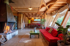 A cozy living room with a fireplace, a red sofa, and a dining area with wooden furniture.