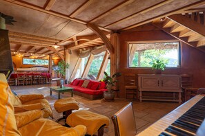 A cozy interior with a piano, wooden furniture, a red sofa, and a dining area.