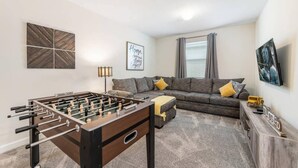 Una sala de estar con una mesa de fútbol, un sofá y una televisión.