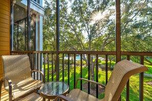 A covered outdoor seating area with chairs and a table, overlooking a well-maintained lawn and trees. - 3BR escape near Disney w/ balconies (Davenport)