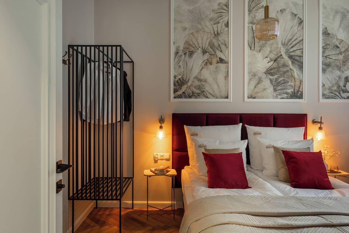 Un dormitorio con cama, perchero, mesita de noche y decoración en la pared.