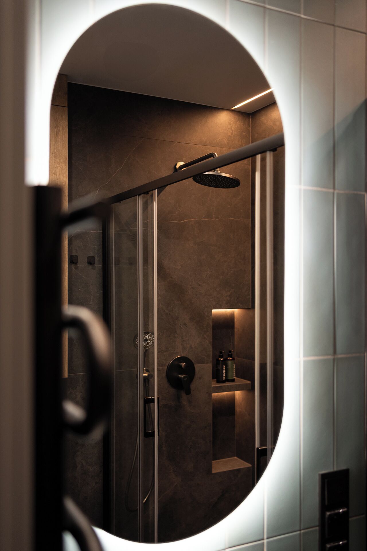 A modern shower enclosure with a glass door, a handheld showerhead, and a towel rack.