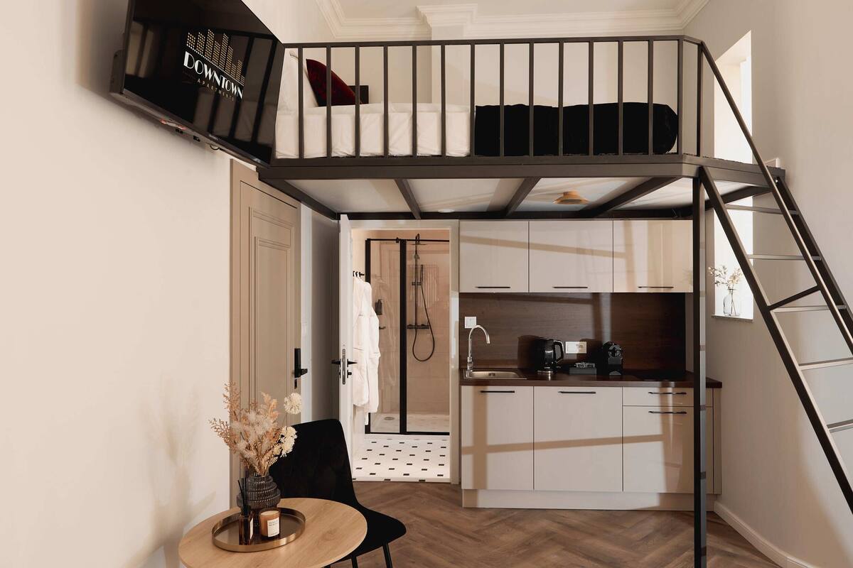 Un apartamento estudio compacto con kitchenette, comedor y baño pequeño.