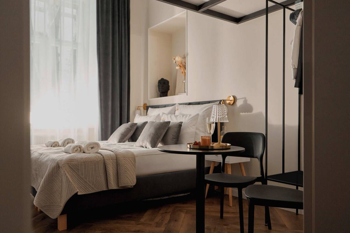 Una habitación de hotel moderna con una cama bien hecha, una mesa redonda con una lámpara y una silla.