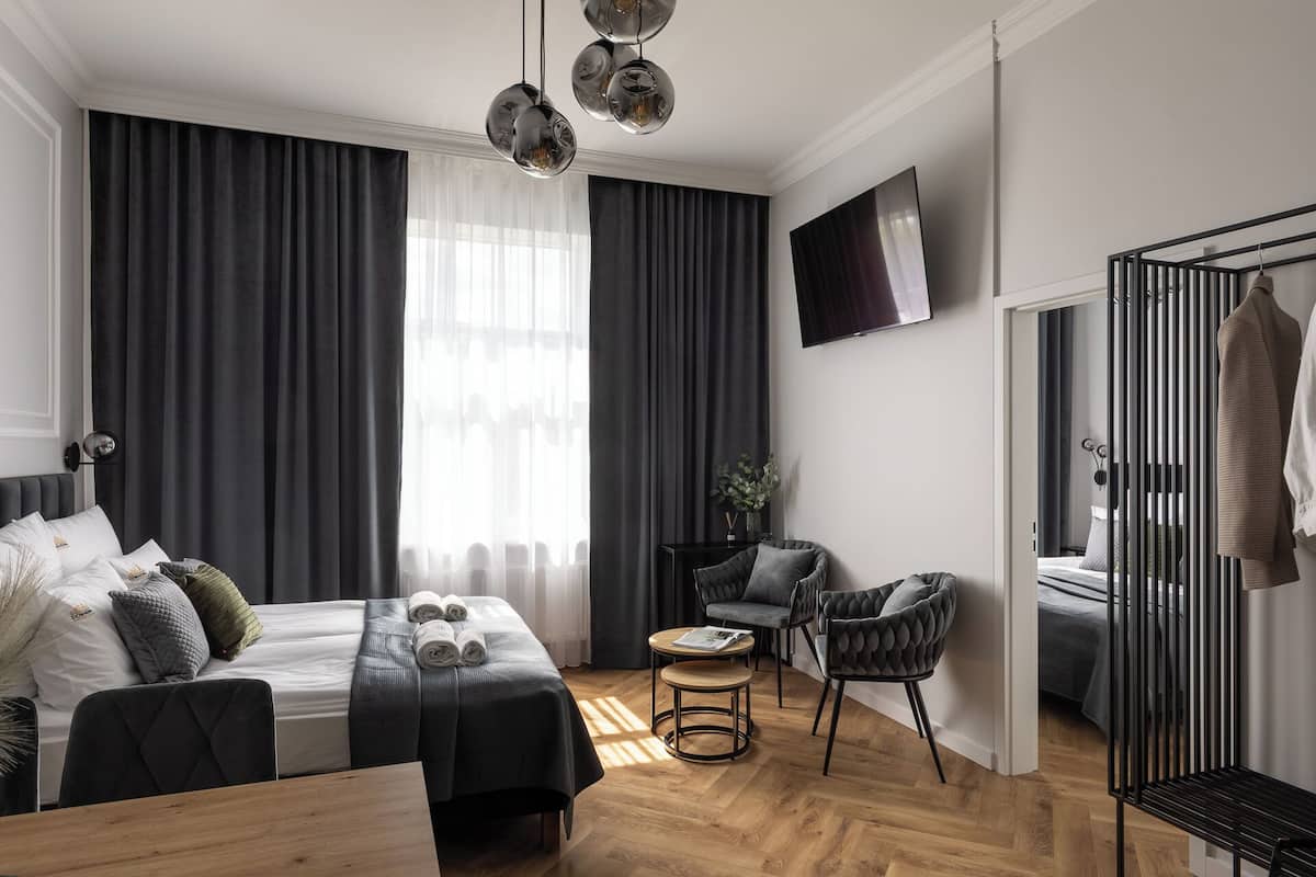Una habitación de hotel moderna con una cama, un área de descanso con una mesa y un televisor fijado a la pared.