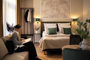 Ein Hotelzimmer mit Bett, Sitzgelegenheit, Kleiderständer und einem Wandbild.