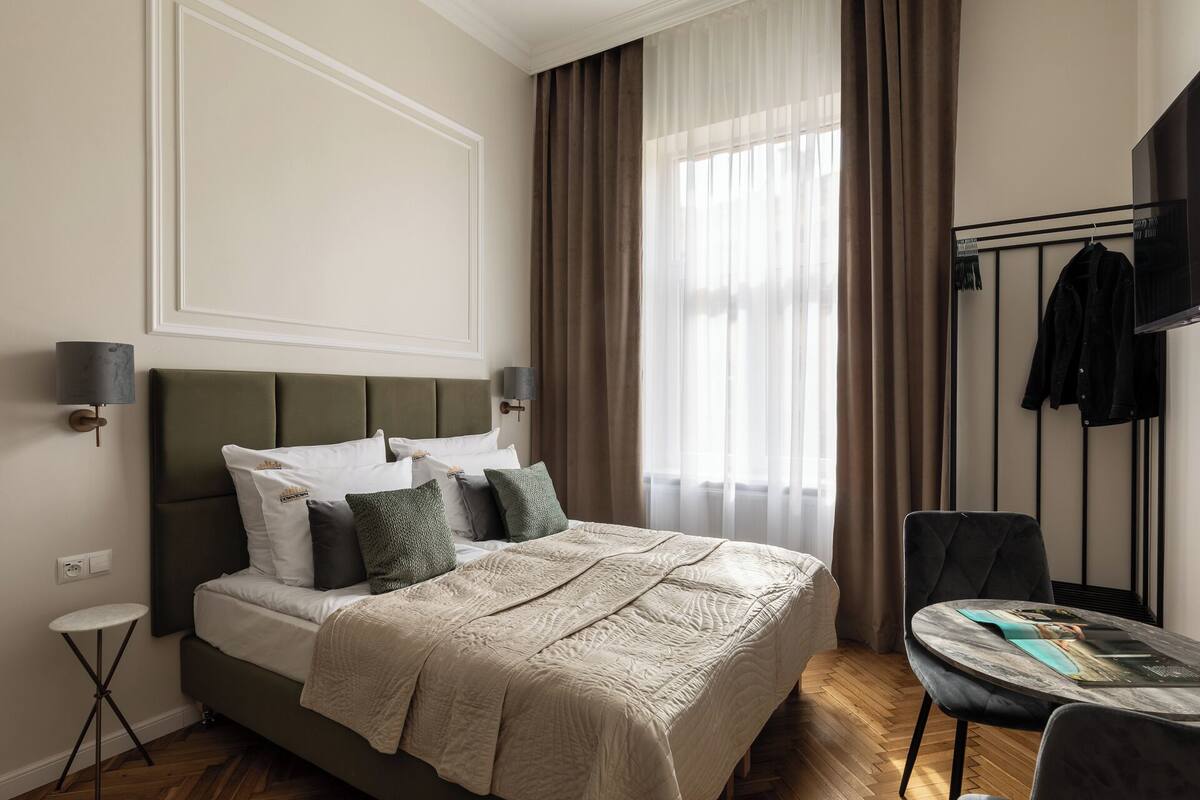 Habitación de hotel impecable con cama, lámparas de noche, una mesita y una silla.