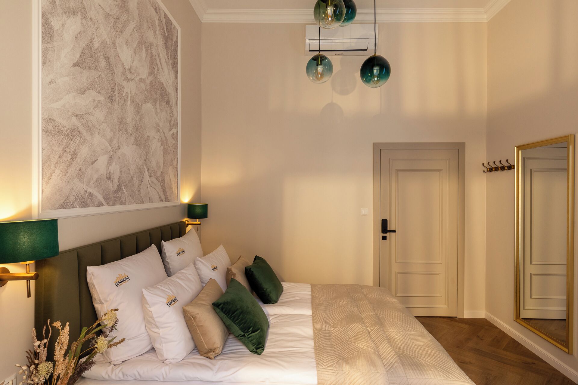 A hotel room with a bed, a wall-mounted artwork, a ceiling light fixture, and a door.