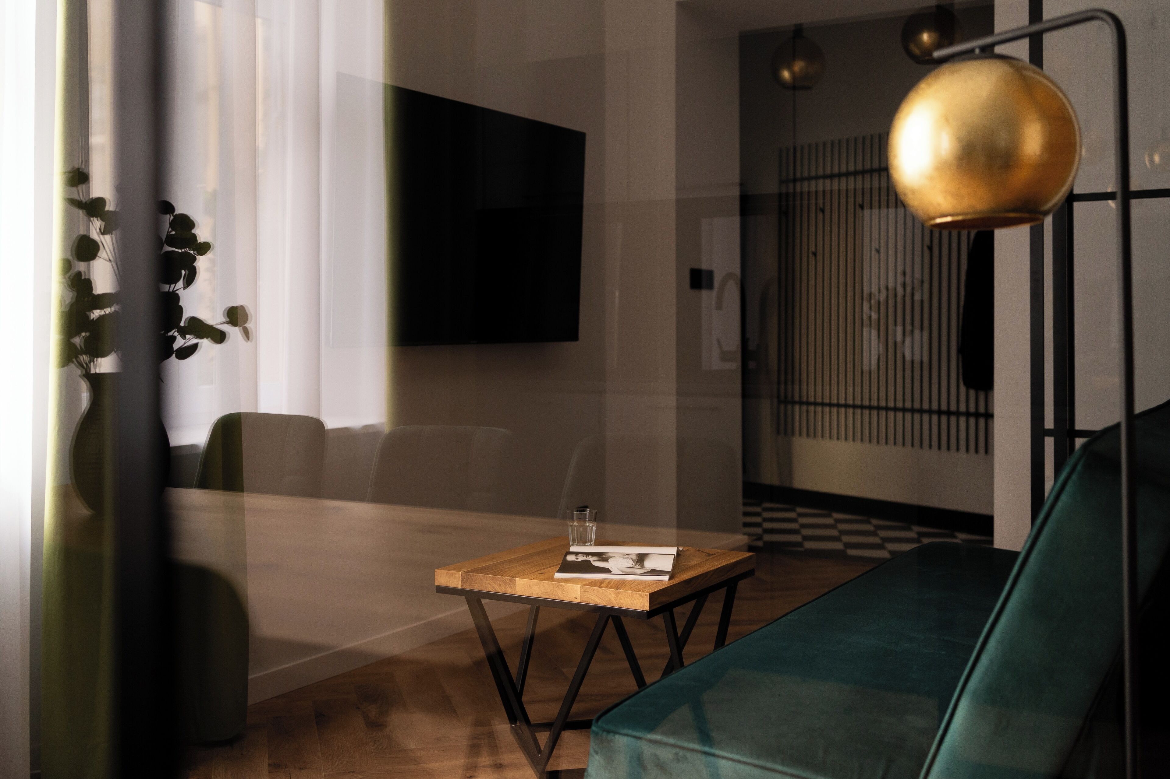 Una sala de estar moderna con una mesa de centro de madera, un sofá verde y un televisor montado en la pared.