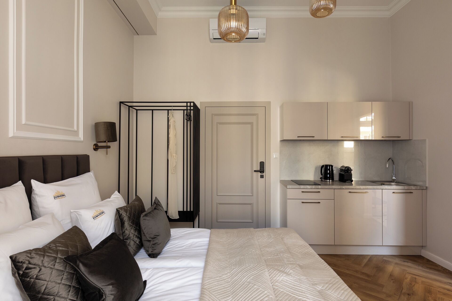A hotel room with a bed, a wardrobe, a kitchenette, and a door.