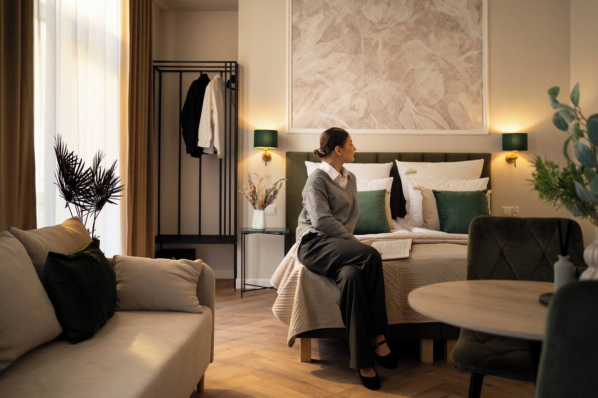 Una habitación de hotel con cama, zona de estar con mesa, sofá y perchero.