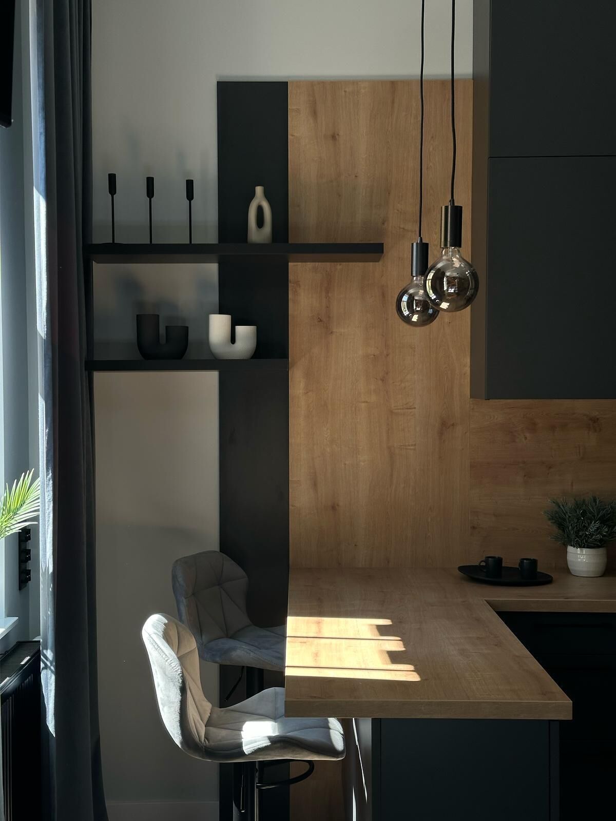 Una cocina moderna con encimera de madera, estantes negros y luces colgantes.