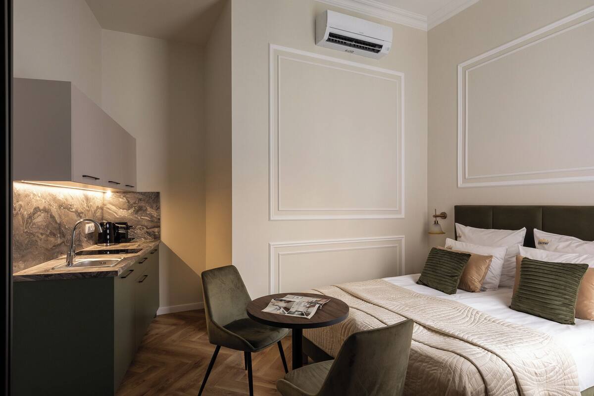 Una habitación de hotel con cama, mesita de noche y un pequeño rincón de descanso con una silla y una mesa.