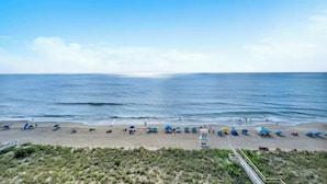 A beach with umbrellas and a lifeguard tower. - Cozy Oceanfront Condo with Heated Pools & Views (Carolina Beach)