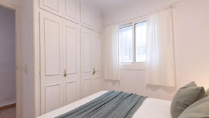 Une chambre à coucher avec un lit, une fenêtre avec des rideaux et une armoire.