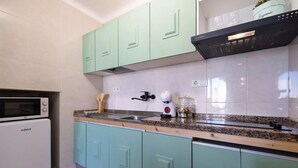Une cuisine avec des armoires de couleur turquoise, un four à micro-ondes, un évier et une cuisinière.
