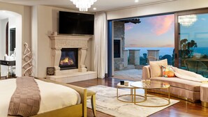 Un dormitorio moderno con chimenea, una cama grande, un sofá y un balcón con vistas.