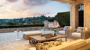 Una terraza en la azotea con mobiliario exterior, un elemento decorativo de fuego y vistas de la ciudad.