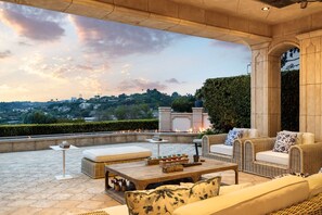 A rooftop patio with outdoor furniture, a fire feature, and a view of the cityscape.