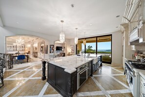 A spacious kitchen with a large island, modern appliances, and a view to the outdoors.