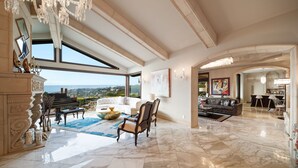 Un salón amplio con un piano de cola, una chimenea y un gran ventanal con vistas al exterior.