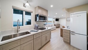 A modern kitchen with a large island, stainless steel appliances, and a view of the sea. - New - Modern Studio - Stunning Ocean View (San Diego)