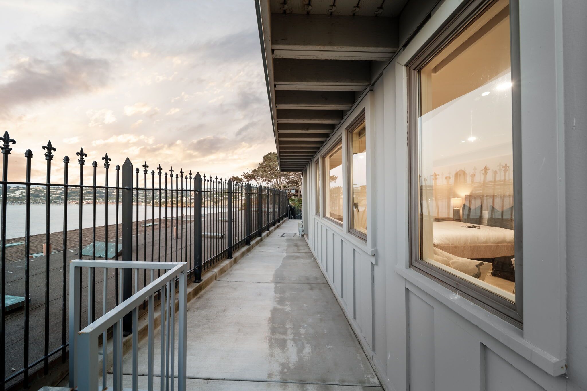 A corridor with a view of a bed and a window overlooking a body of water.