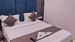 A modern bedroom with a bed, a ceiling fan, and an air conditioning unit. - Hotel S S Town (Vadodara)