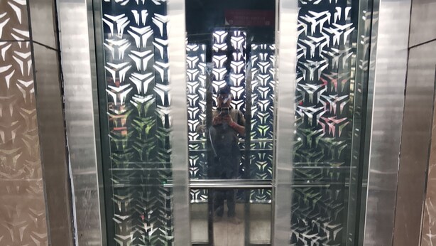 An elevator with patterned glass doors and metallic walls. - Hotel S S Town (Vadodara)